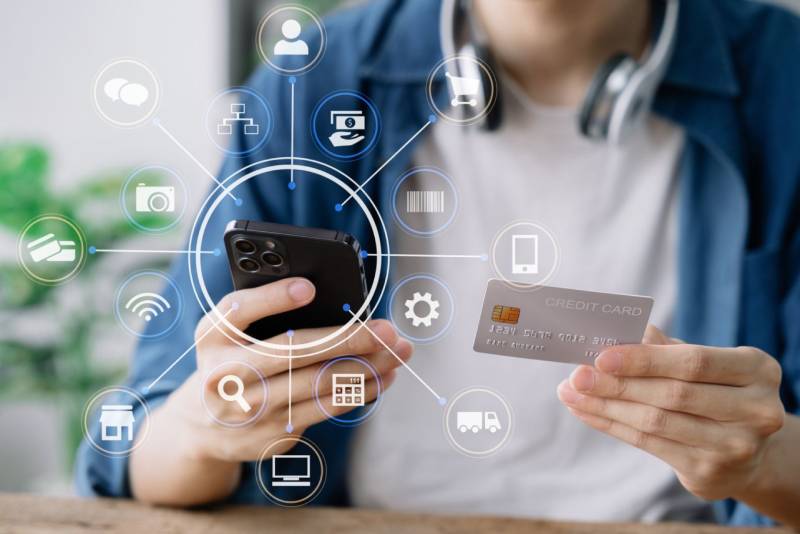 Person holding a smartphone and credit card with digital payment icons.