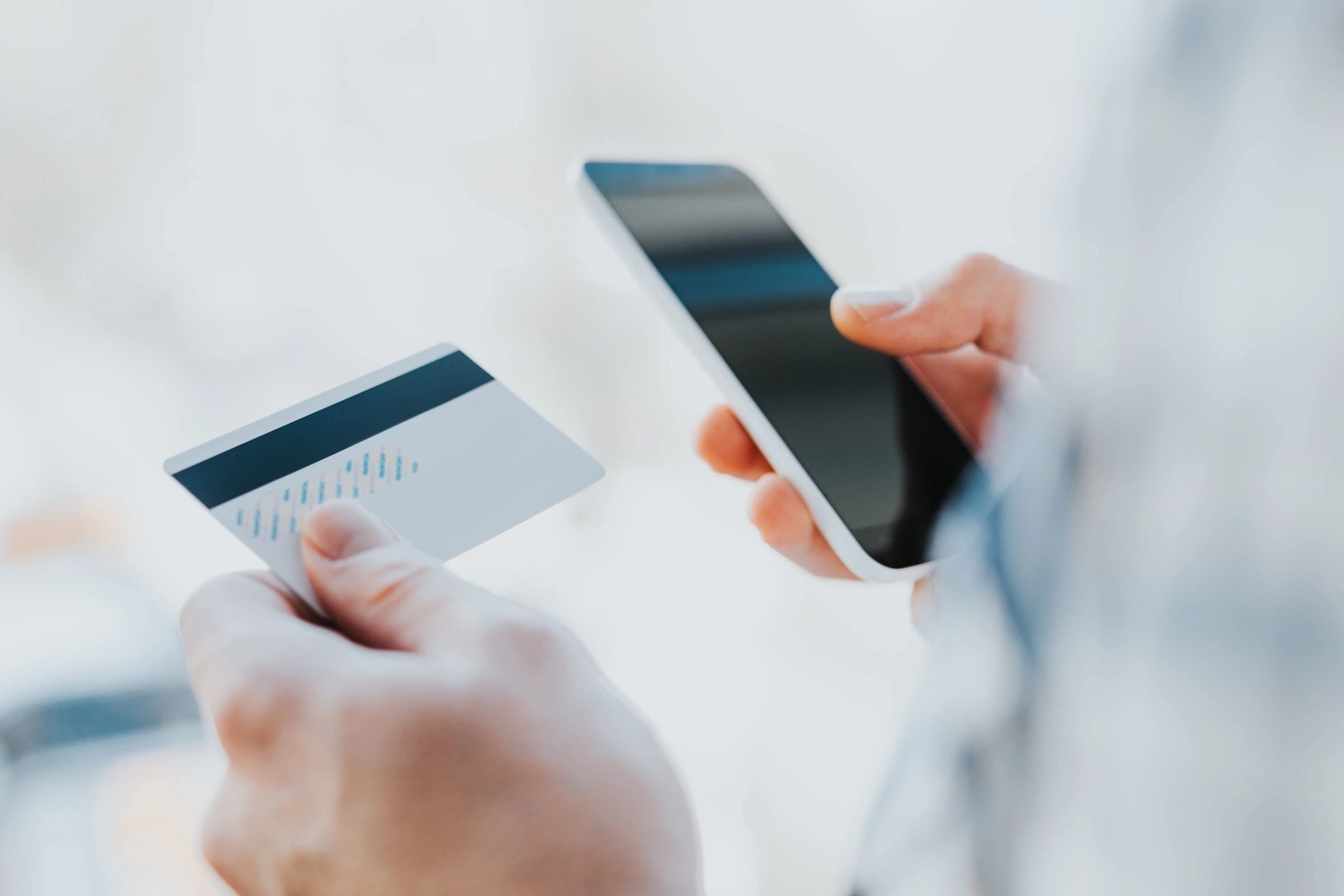 Person holding a credit card and smartphone for online payment.